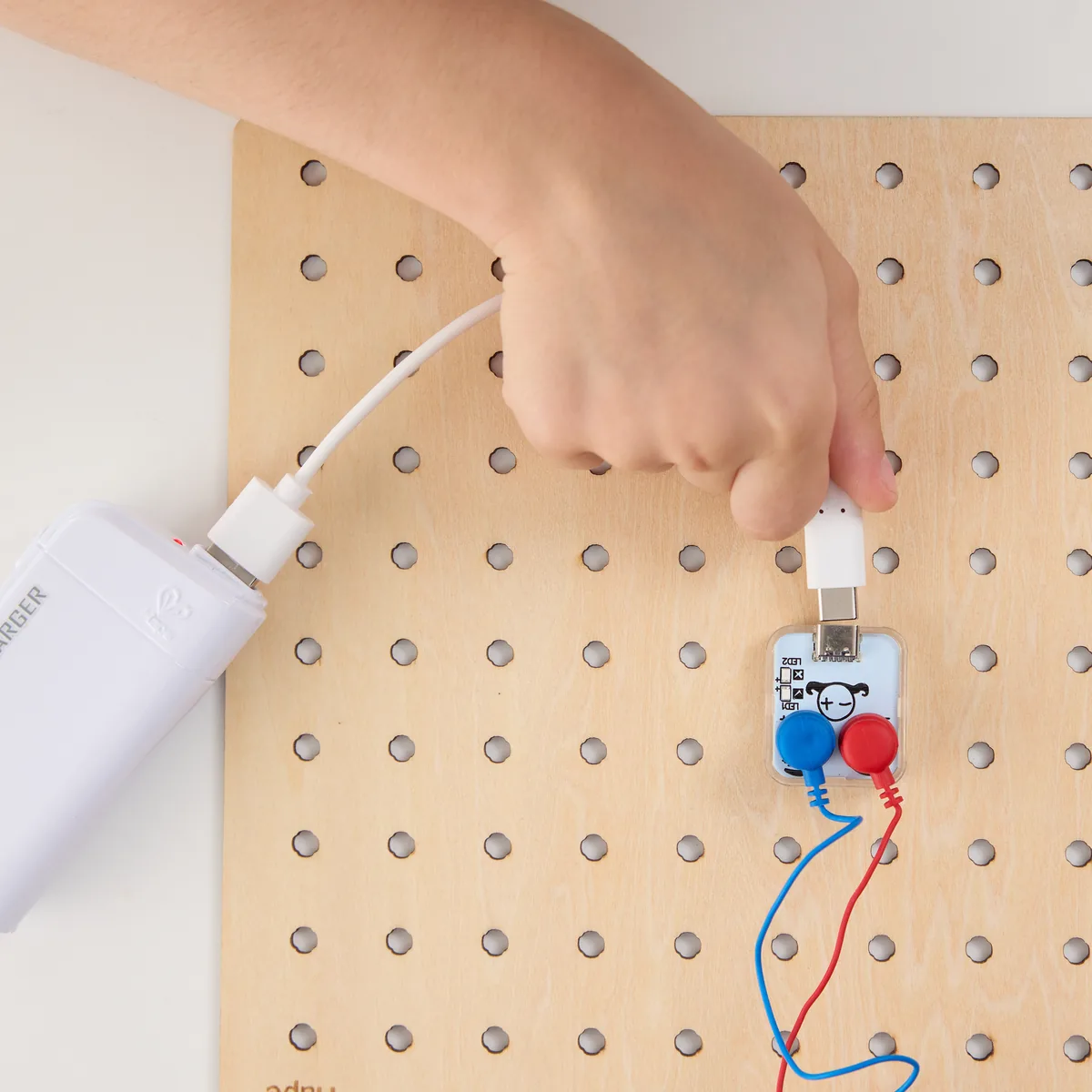 A hand pressing a Labbox block onto the wooden circuit board