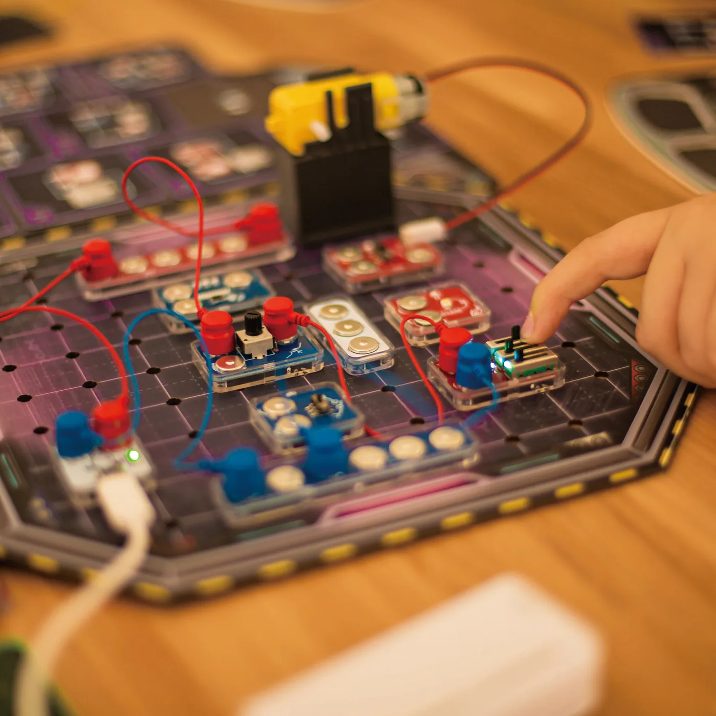 Hands snapping blocks into a circuit on the game board